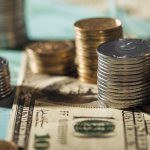 selective focus of ukrainian coins stacks on dollar banknotes with blurred background